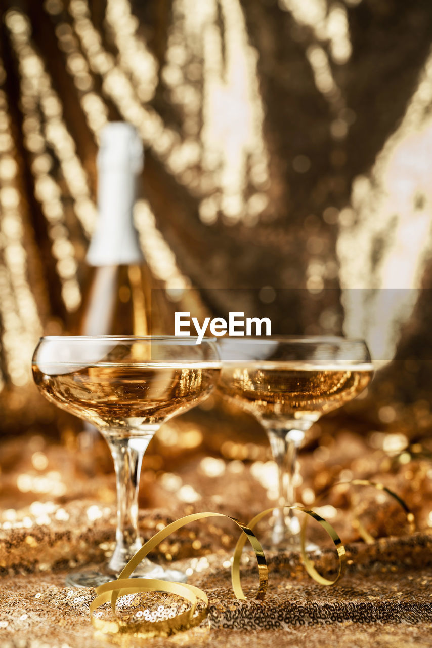 New year concept. new years eve gold party table with two champagne glasses with bottle