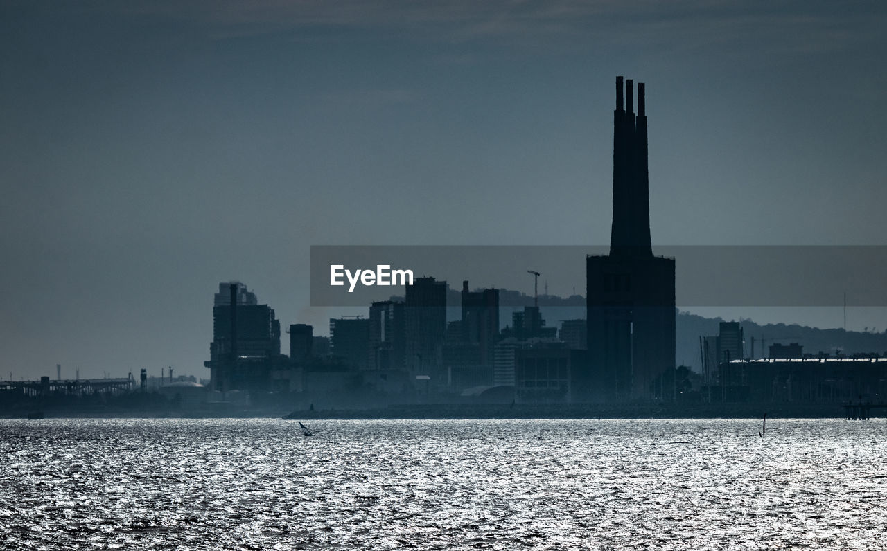 SEA BY BUILDINGS AGAINST SKY IN CITY AGAINST CLEAR BLUE BACKGROUND