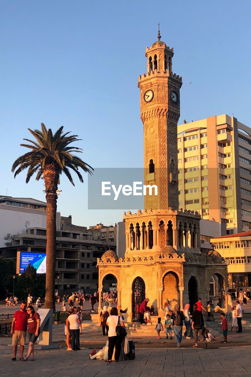 People at clock tower against sky