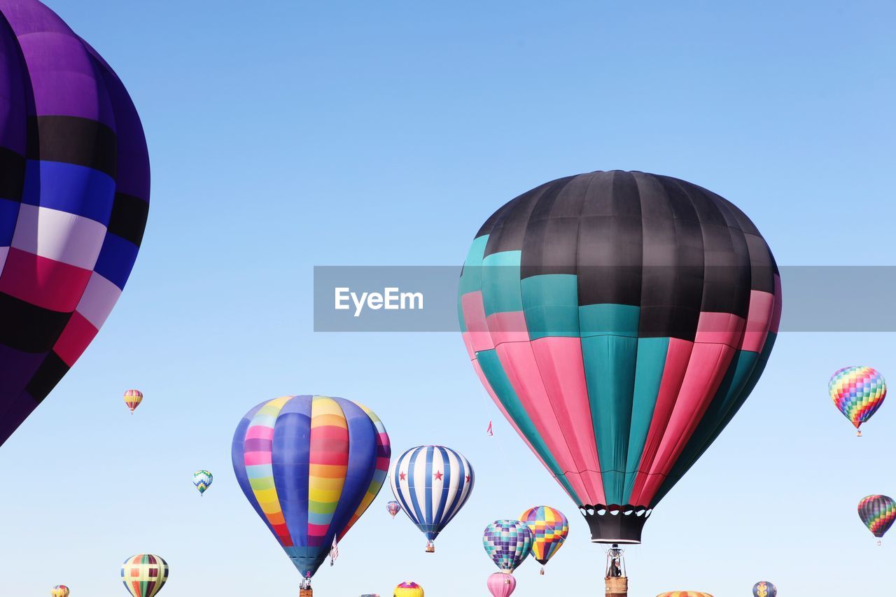 Low angle view of hot air balloons flying against clear blue sky