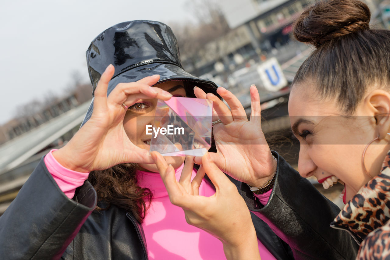 Smiling friends holding crystal in city