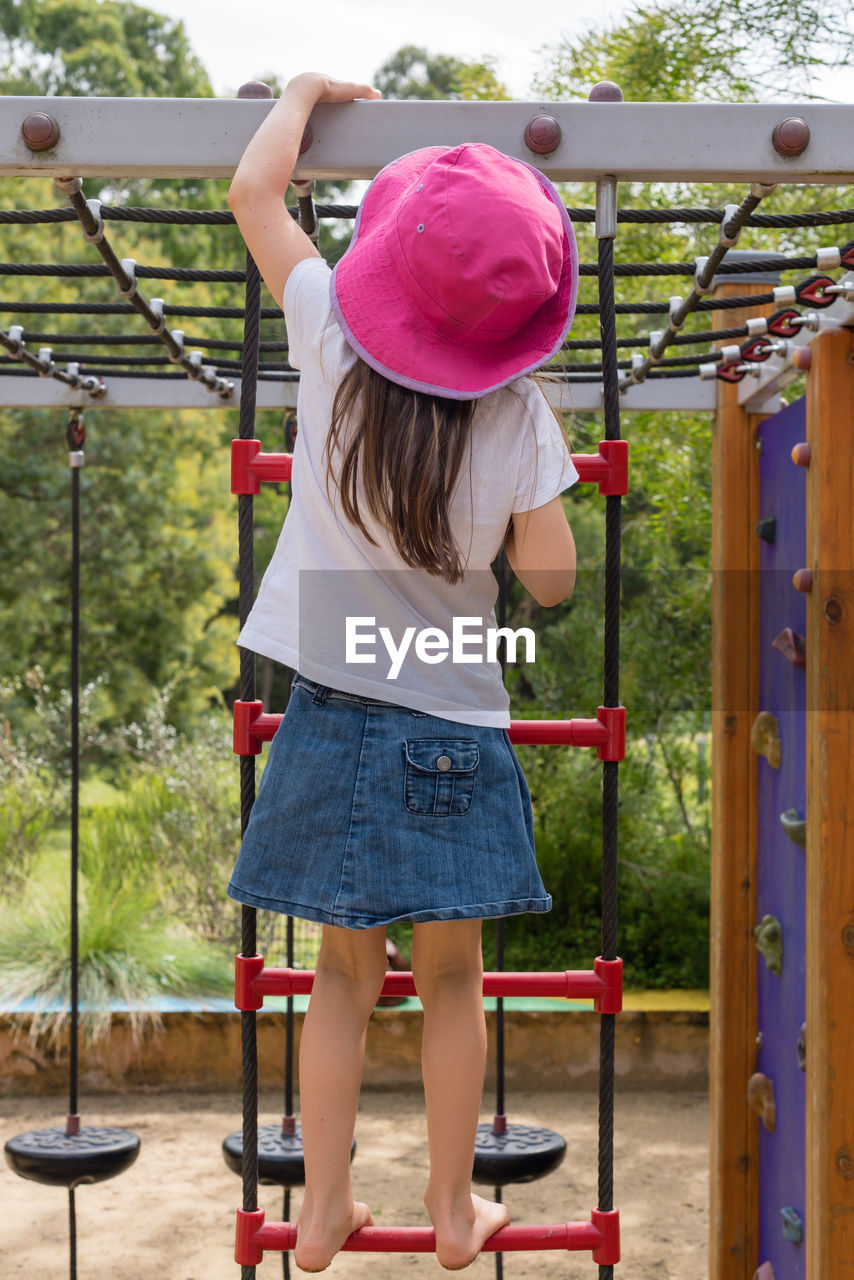 Rear view of girl climbing jungle gym in park