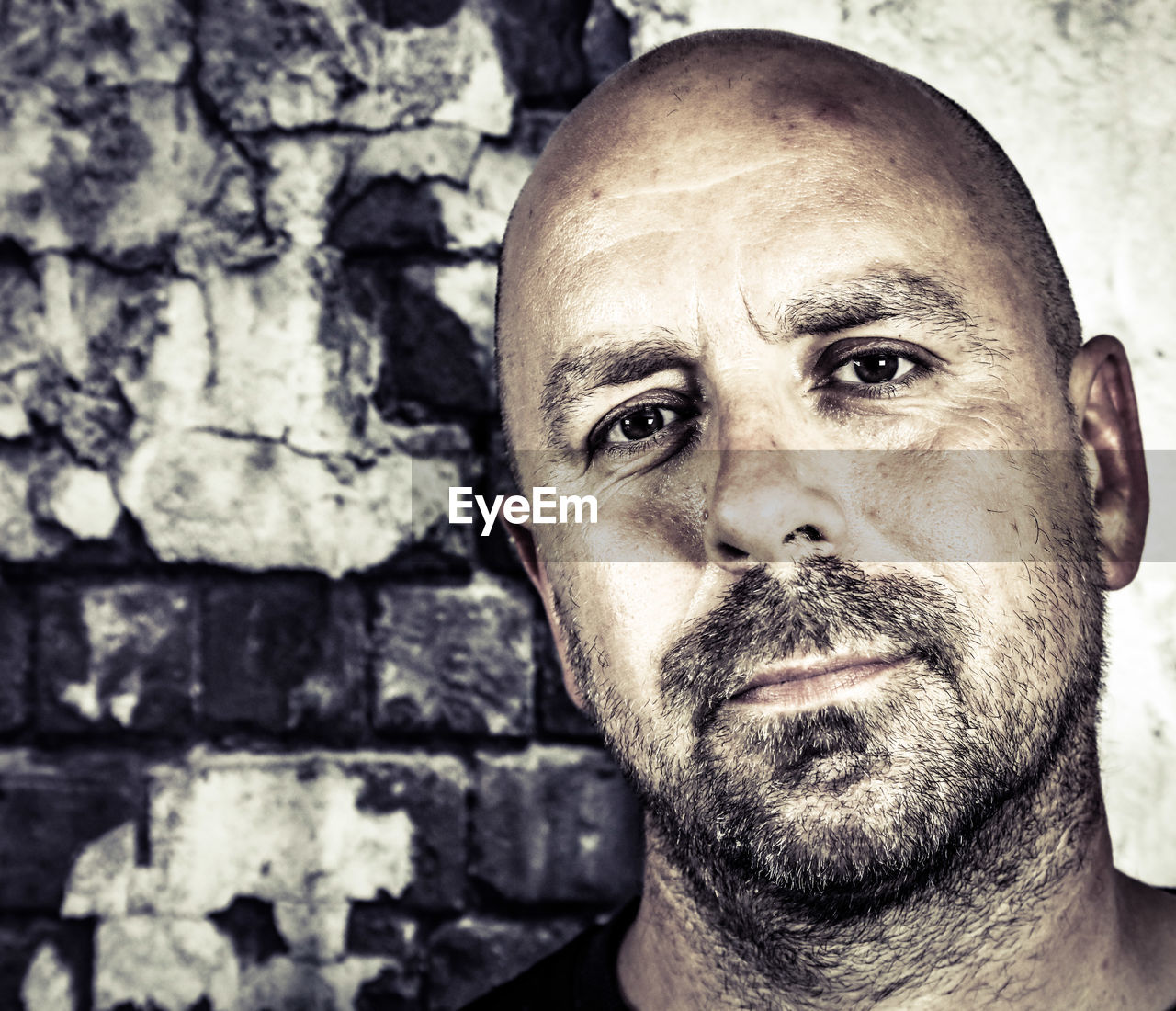 Close-up portrait of mid adult man standing against weathered wall