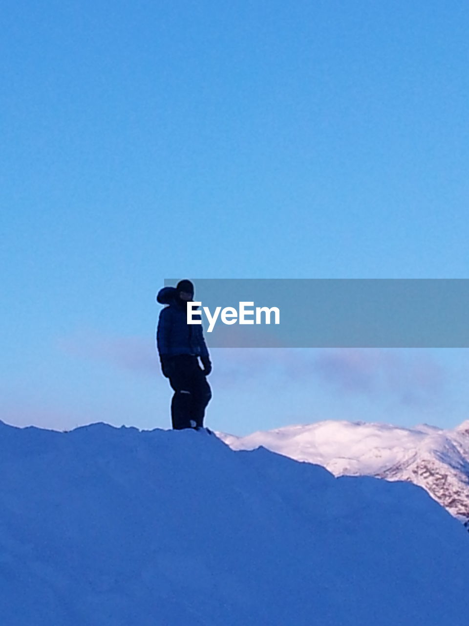 LOW ANGLE VIEW OF PEOPLE STANDING ON SNOW COVERED MOUNTAIN