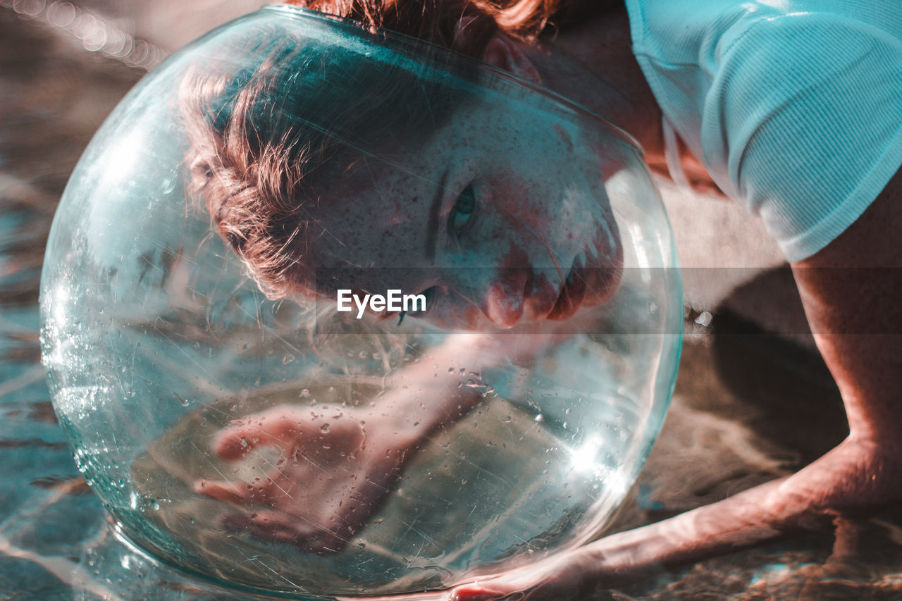 Close-up of woman wearing glass container at lake