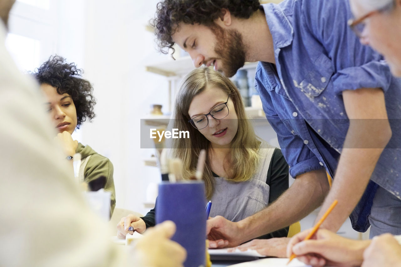 Females looking at man drawing at table