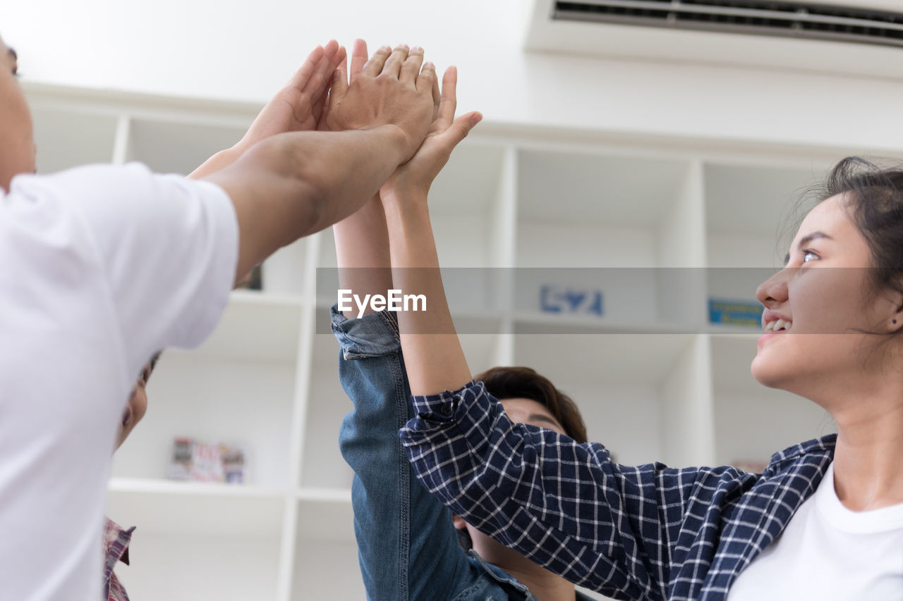 Cheerful colleagues touching hands in office