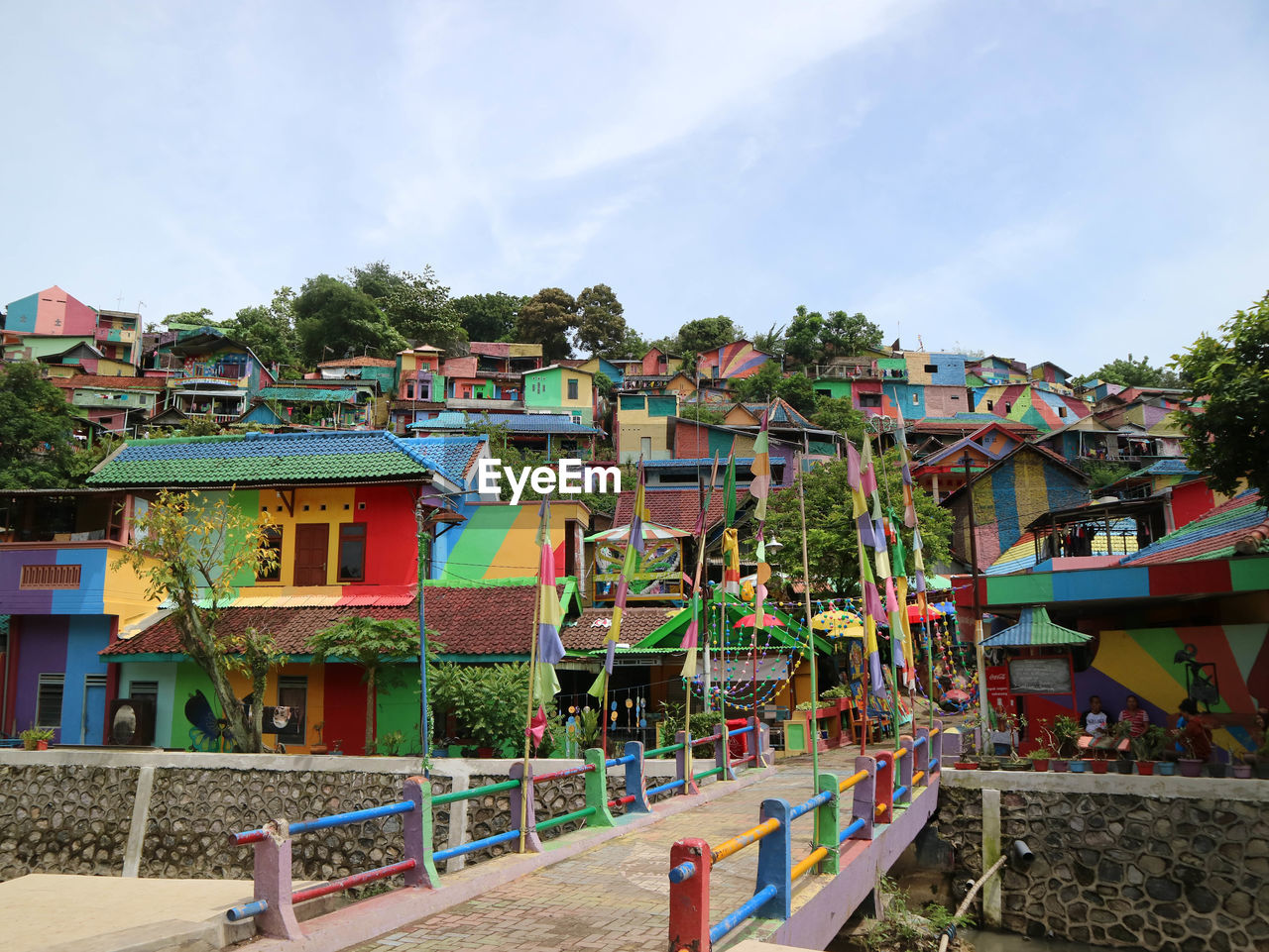 MULTI COLORED HOUSES BY BUILDINGS AGAINST SKY