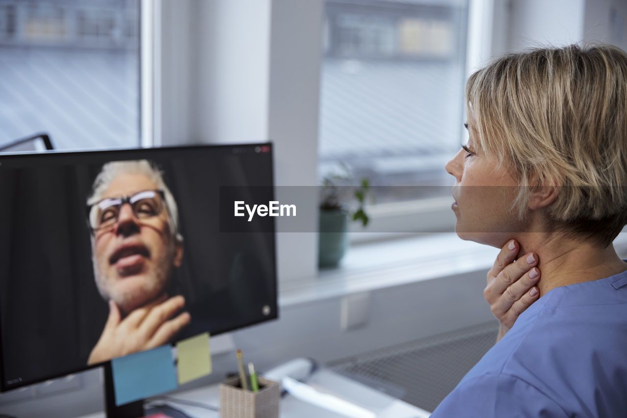 Female doctor having online consultation with senior patient