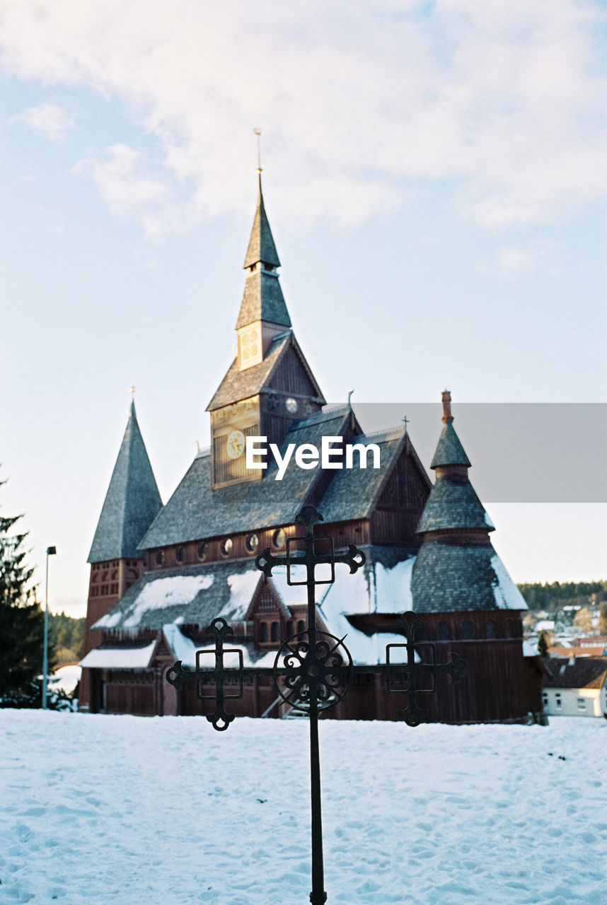 CHURCH BY BUILDINGS AGAINST SKY DURING WINTER