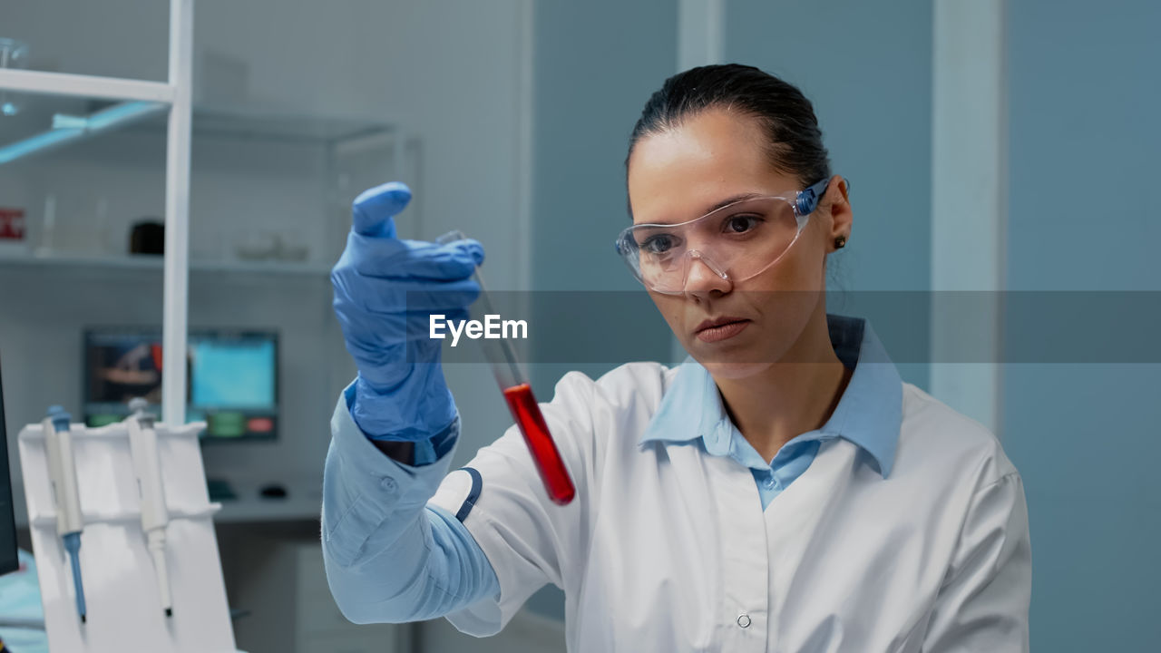 portrait of female doctor holding dentures while standing in laboratory