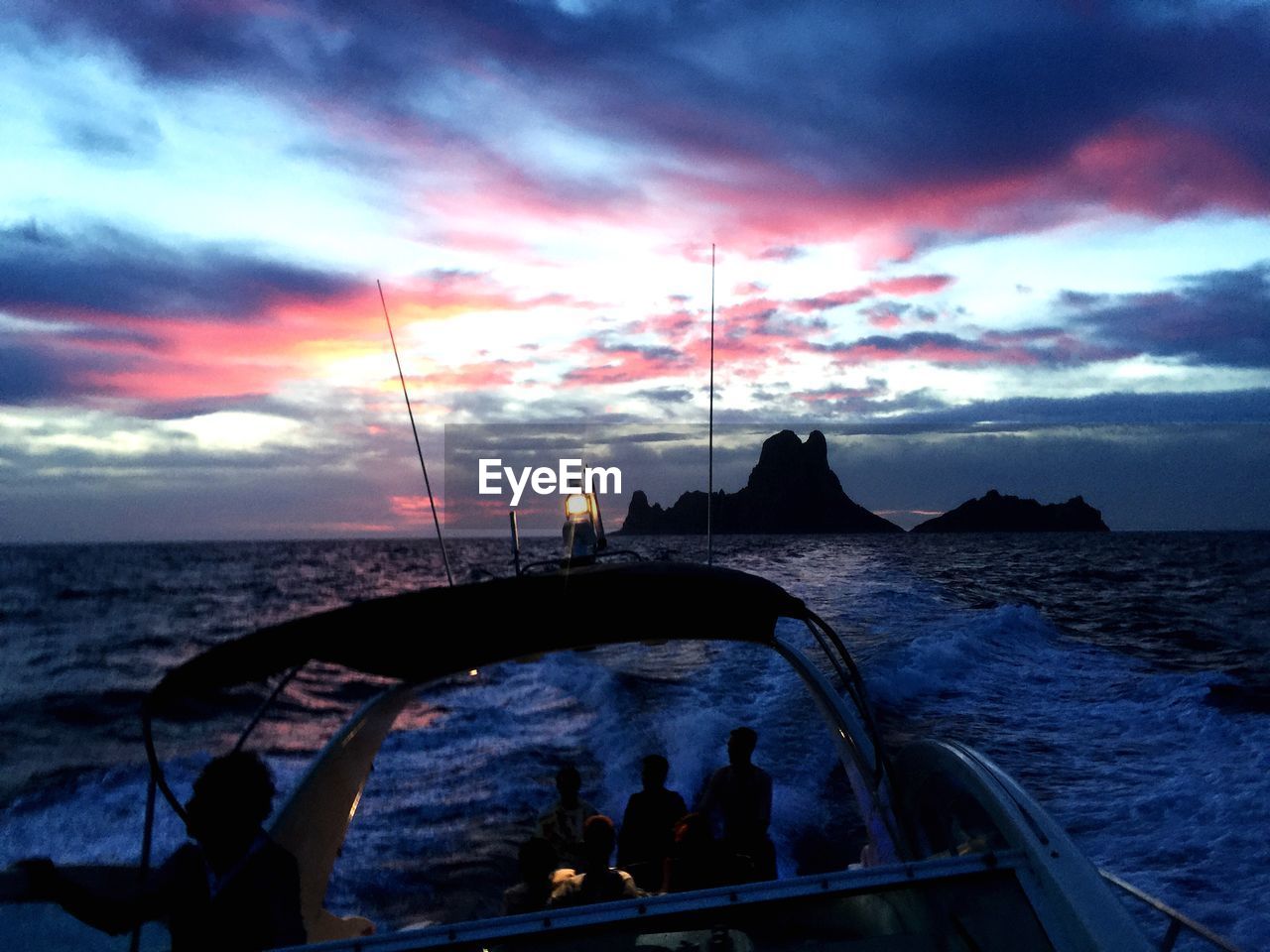 Cropped image of motorboat sailing on sea against sky during sunset