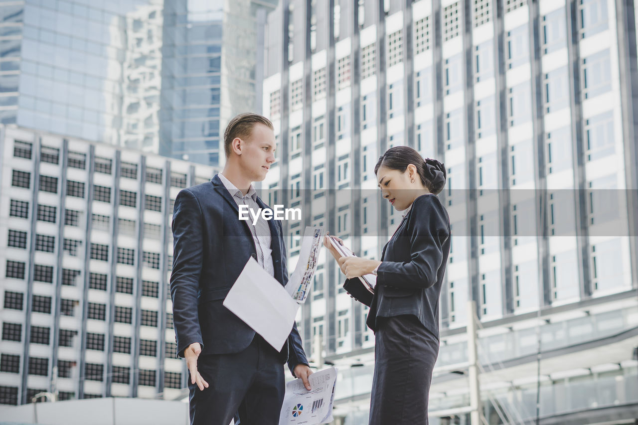 Business people discussing while standing against building