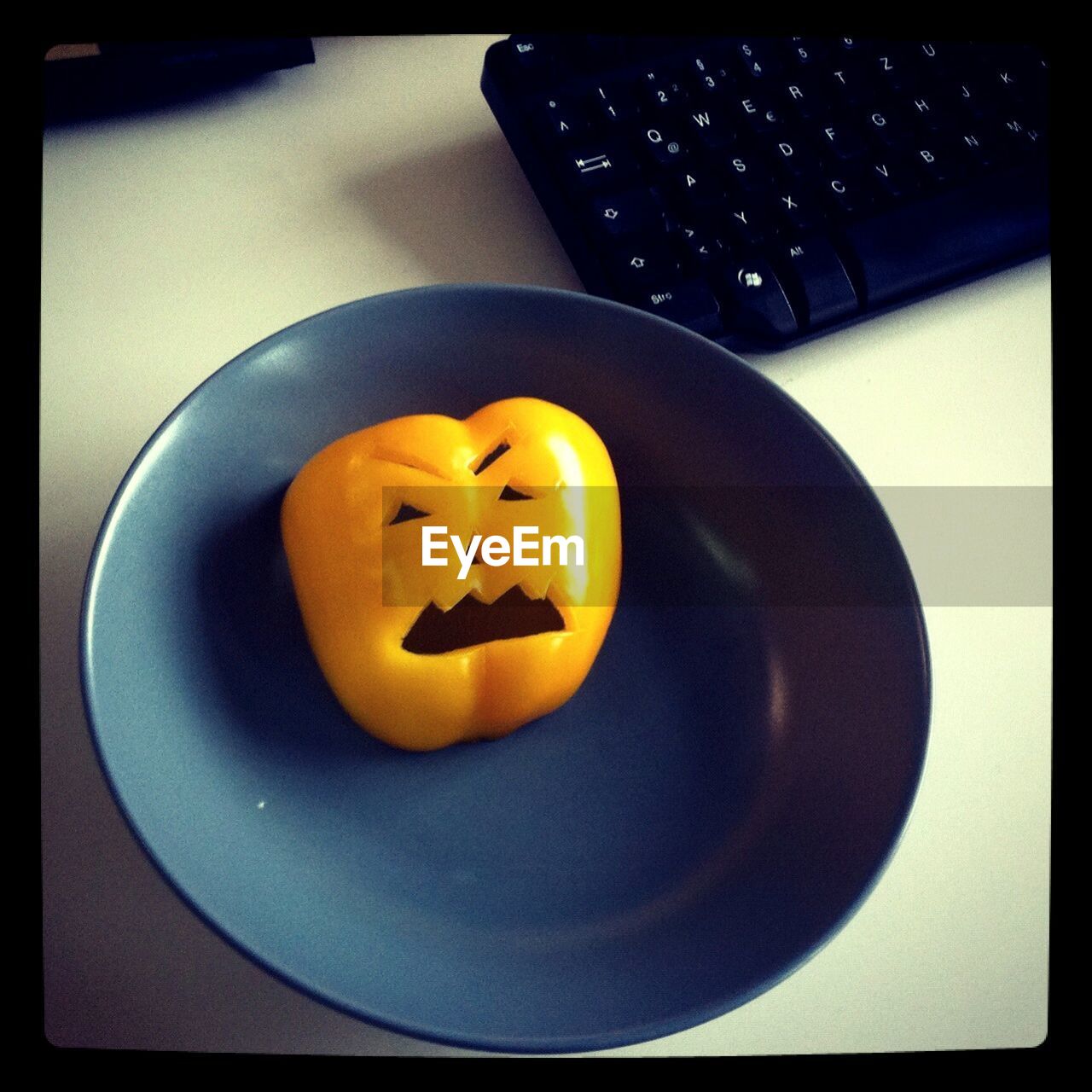 High angle view of face carved on orange bell pepper in plate