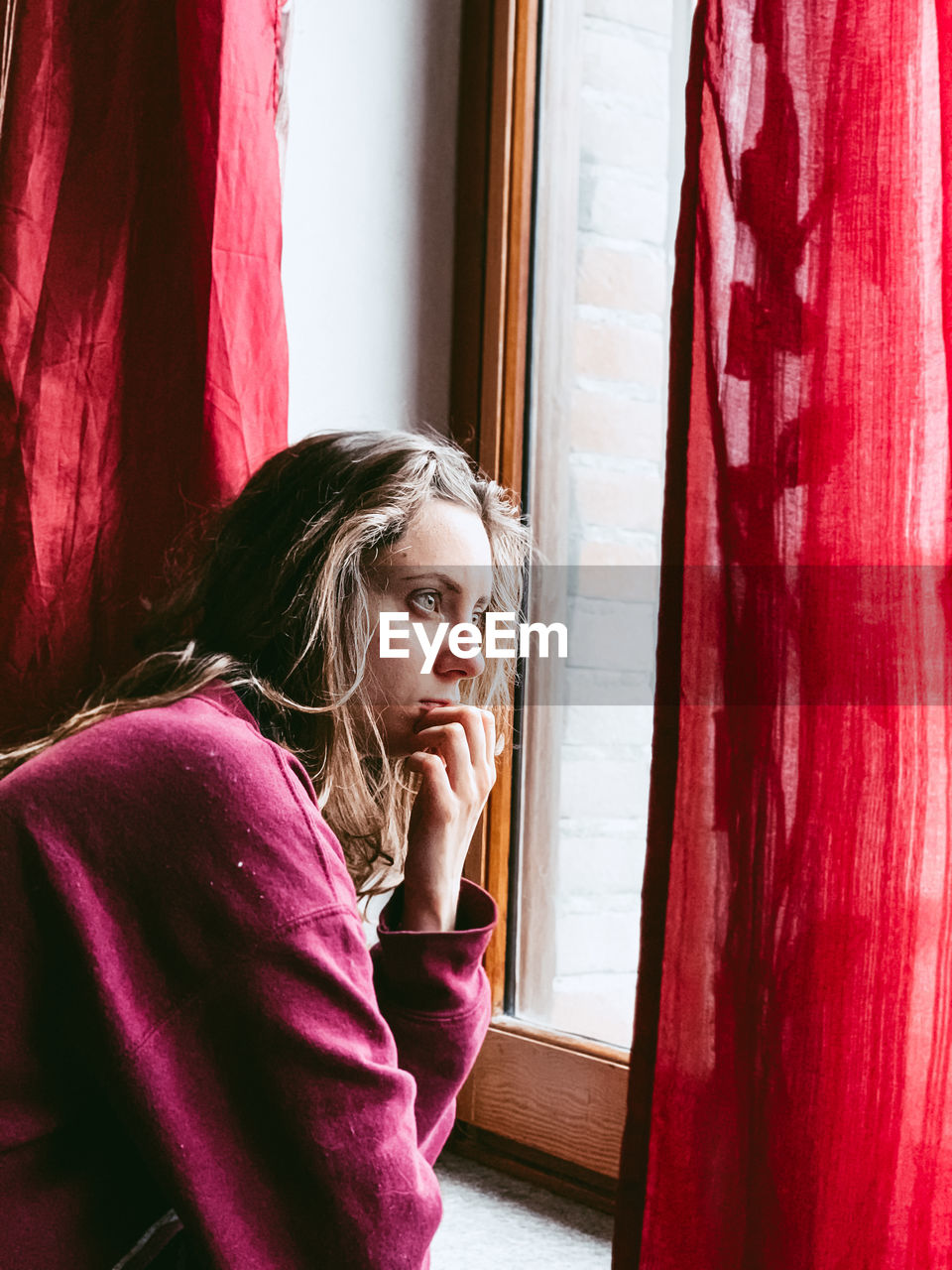 Young woman looking through window