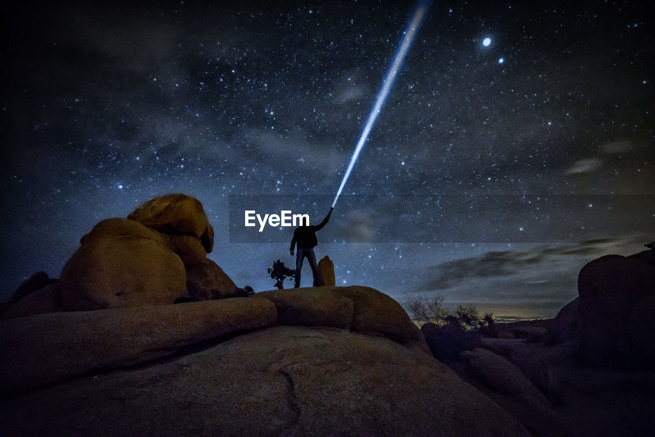 Low angle view of man sitting against sky at night