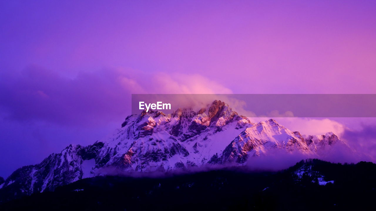 Scenic view of snowcapped mountains against sky at sunset