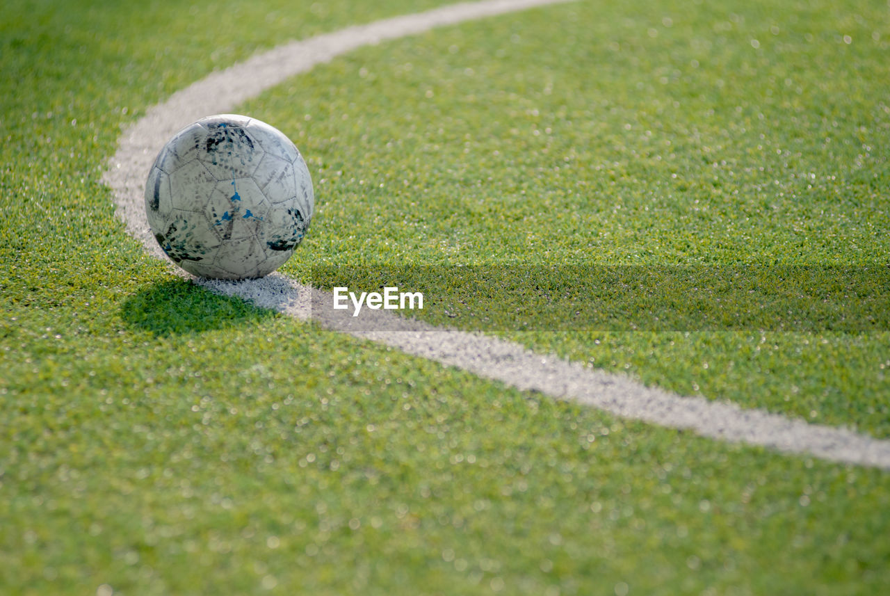 The football ball is located on a curve line in a soccer field.