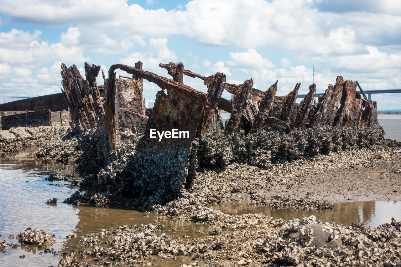 Shipwreck at sea shore against sky