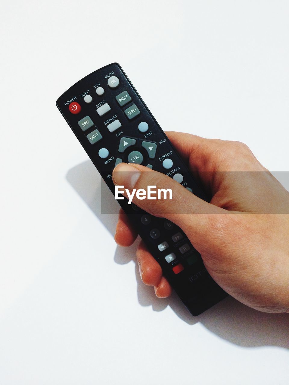 Cropped image of woman holding remote control over white background