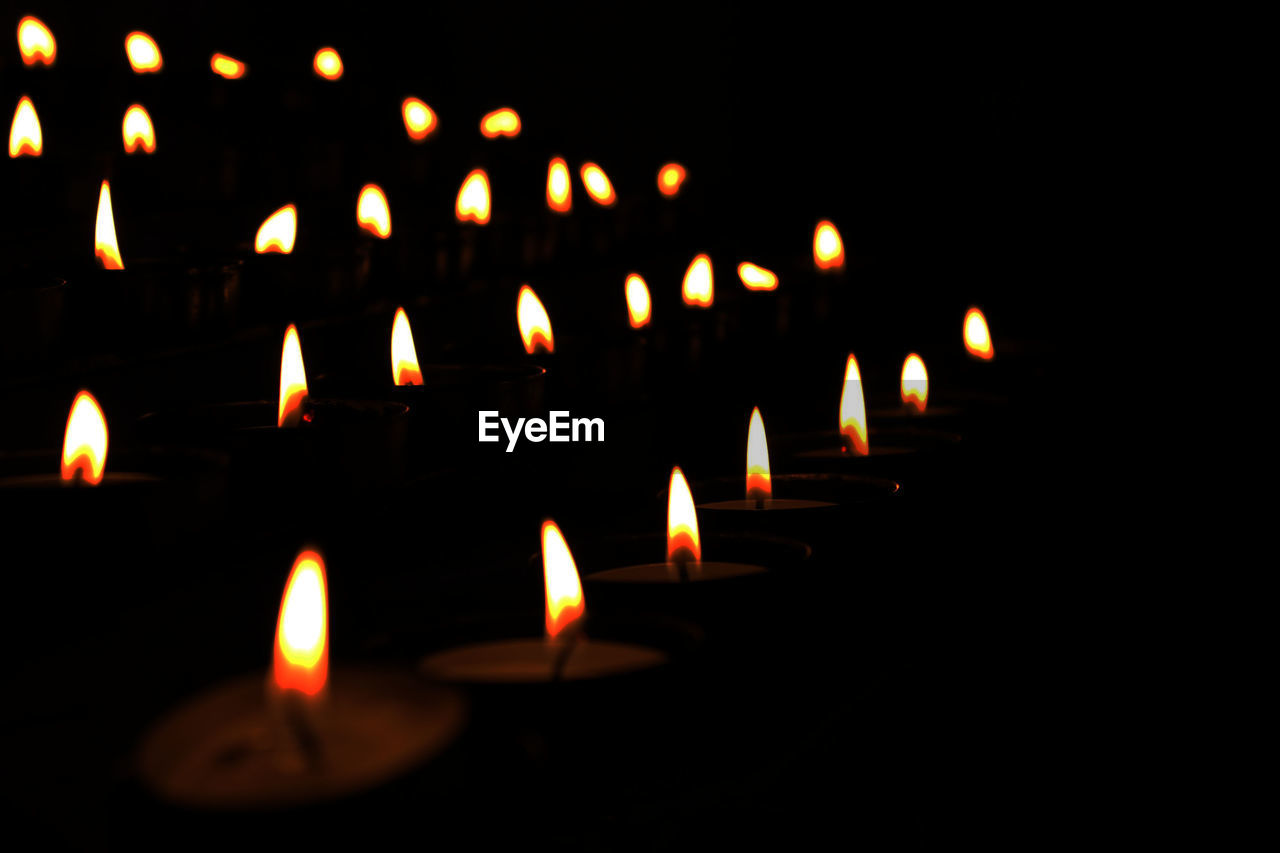 Close-up of candles burning at night