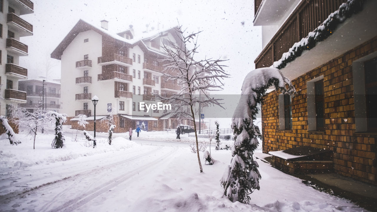 Snow covered street amidst buildings in city