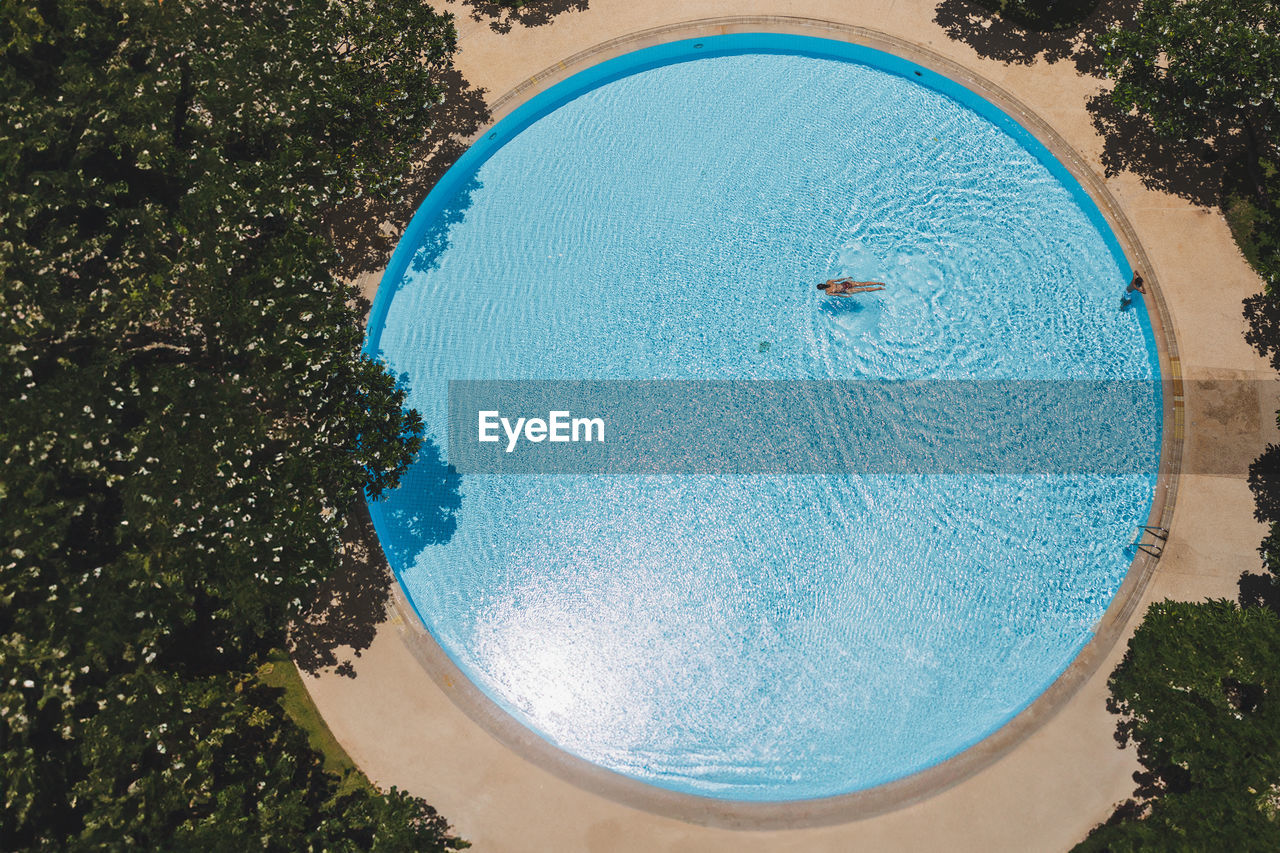 Top view of woman swimming in swimming pool minimal concept.