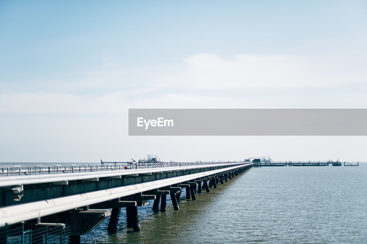 Pier with gas pipelines over sea against sky
