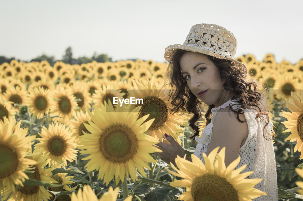 Close-up portrait of young woman standing in sunflower field