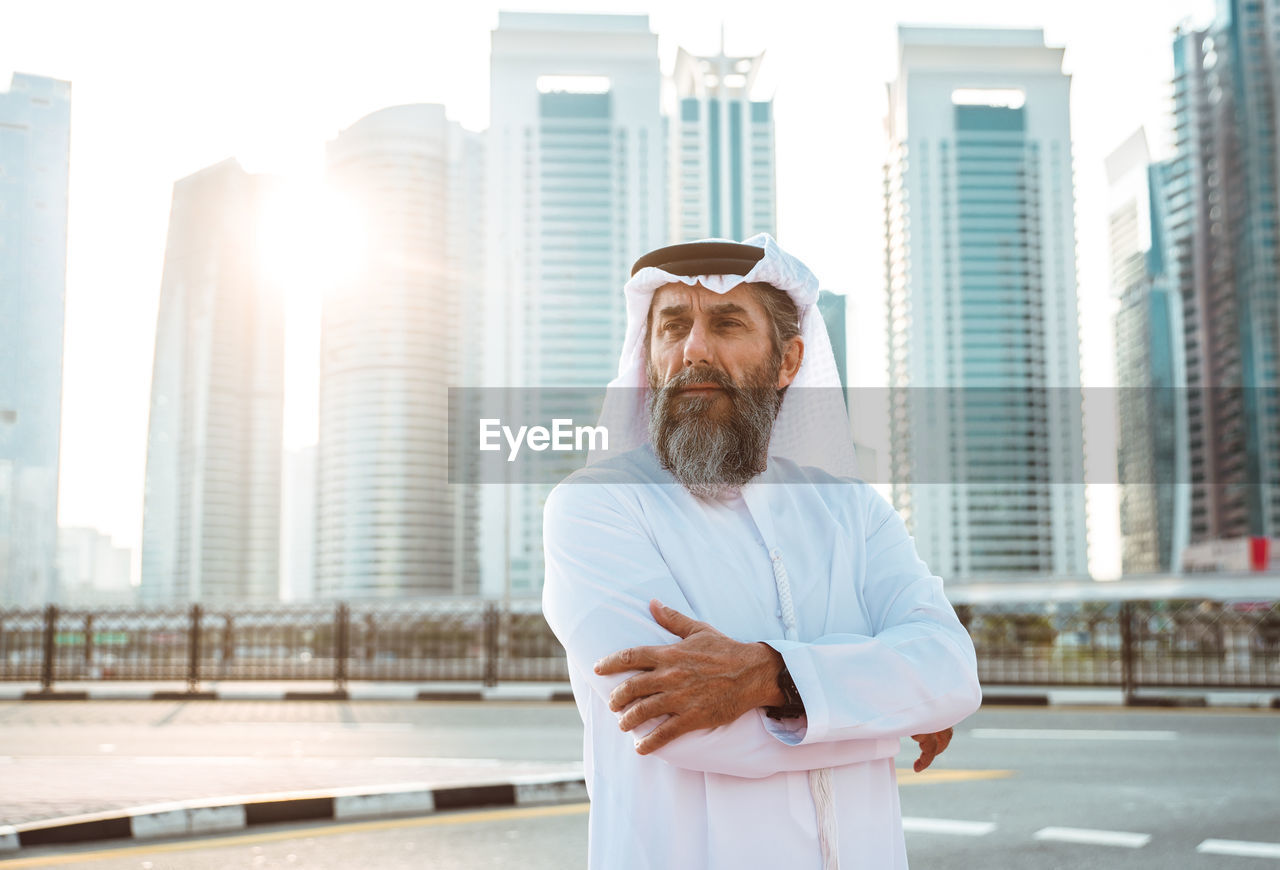 Thoughtful man wearing dish dash standing on street in city