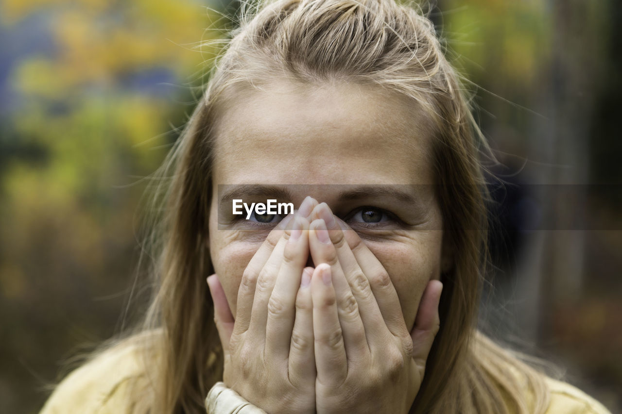 Close-up portrait of woman with hands covering mouth