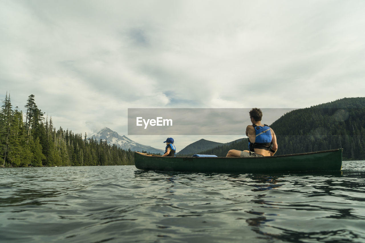 A young girl rides in a canoe with her dad on lost lake in oregon.