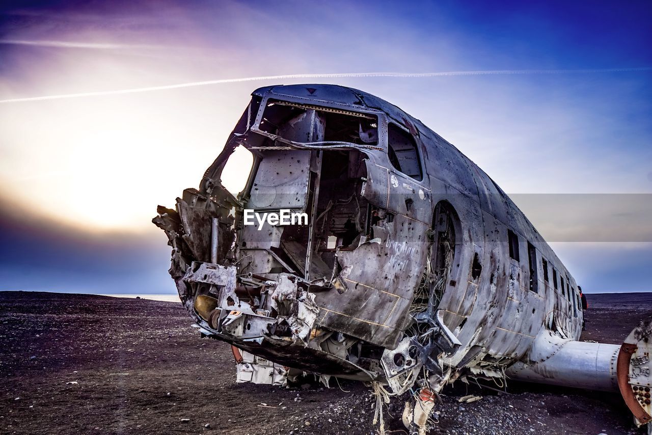 Abandoned airplane on landscape against sky