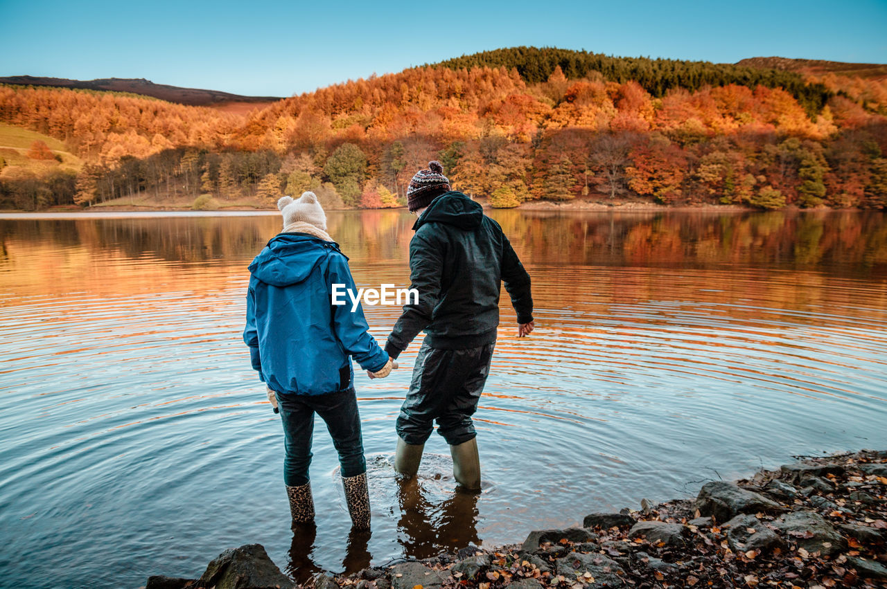 Rear view of friends standing on water at ladybower reservoir