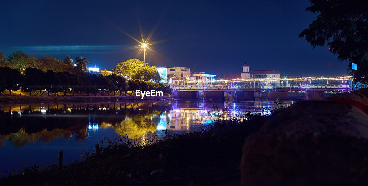 Reflection of trees and illuminated building on river at night