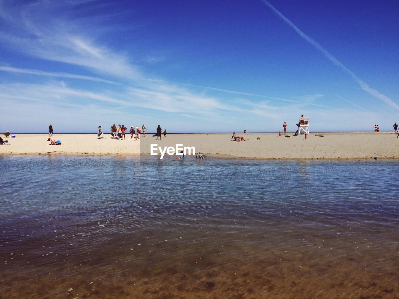 People enjoying on beach against blue sky