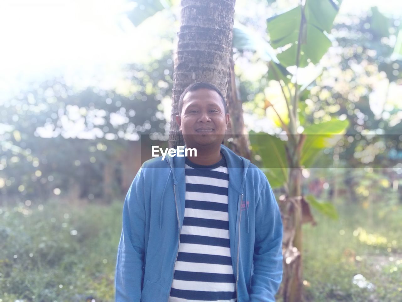 PORTRAIT OF YOUNG MAN STANDING ON TREE