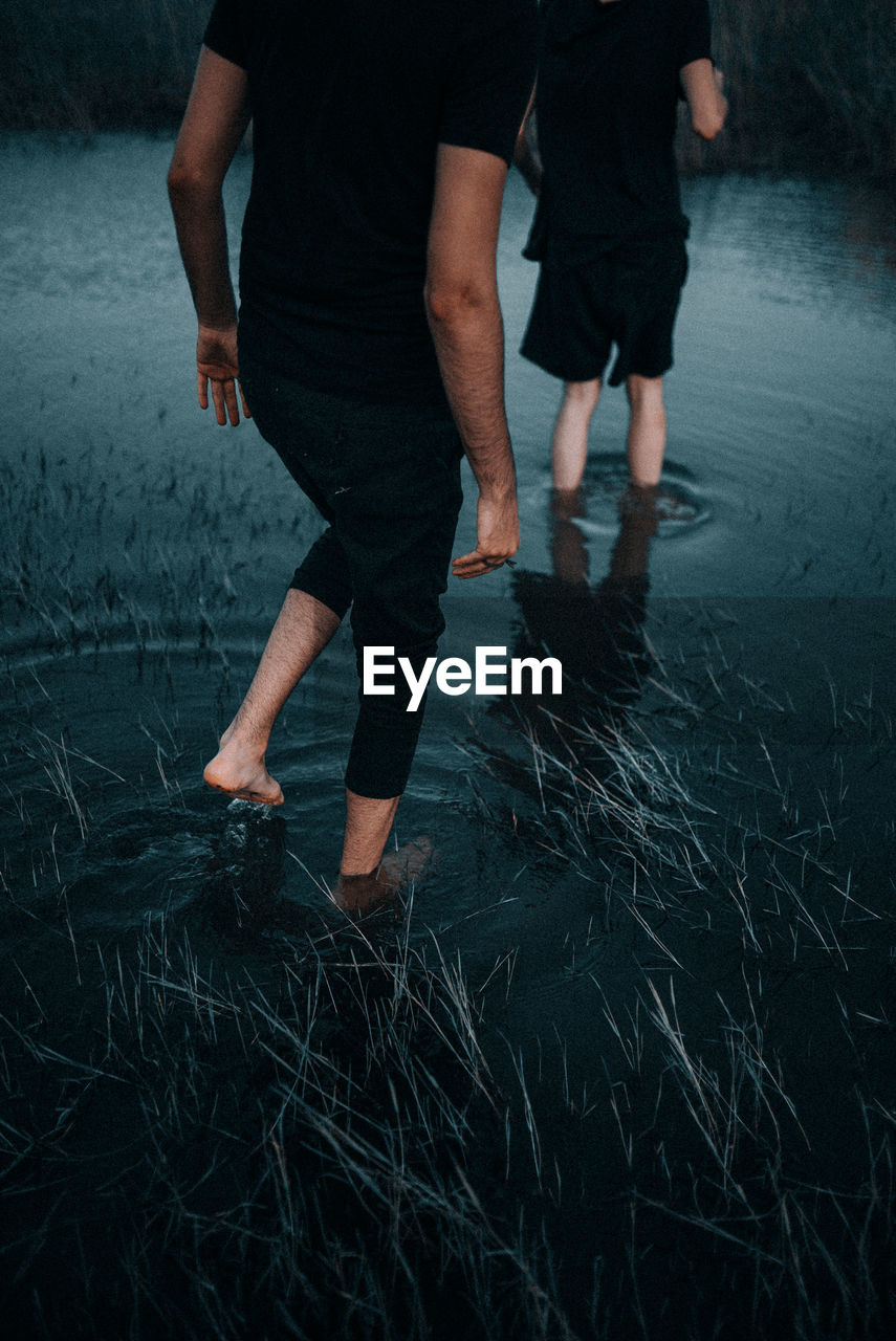 Low section of couple walking in lake