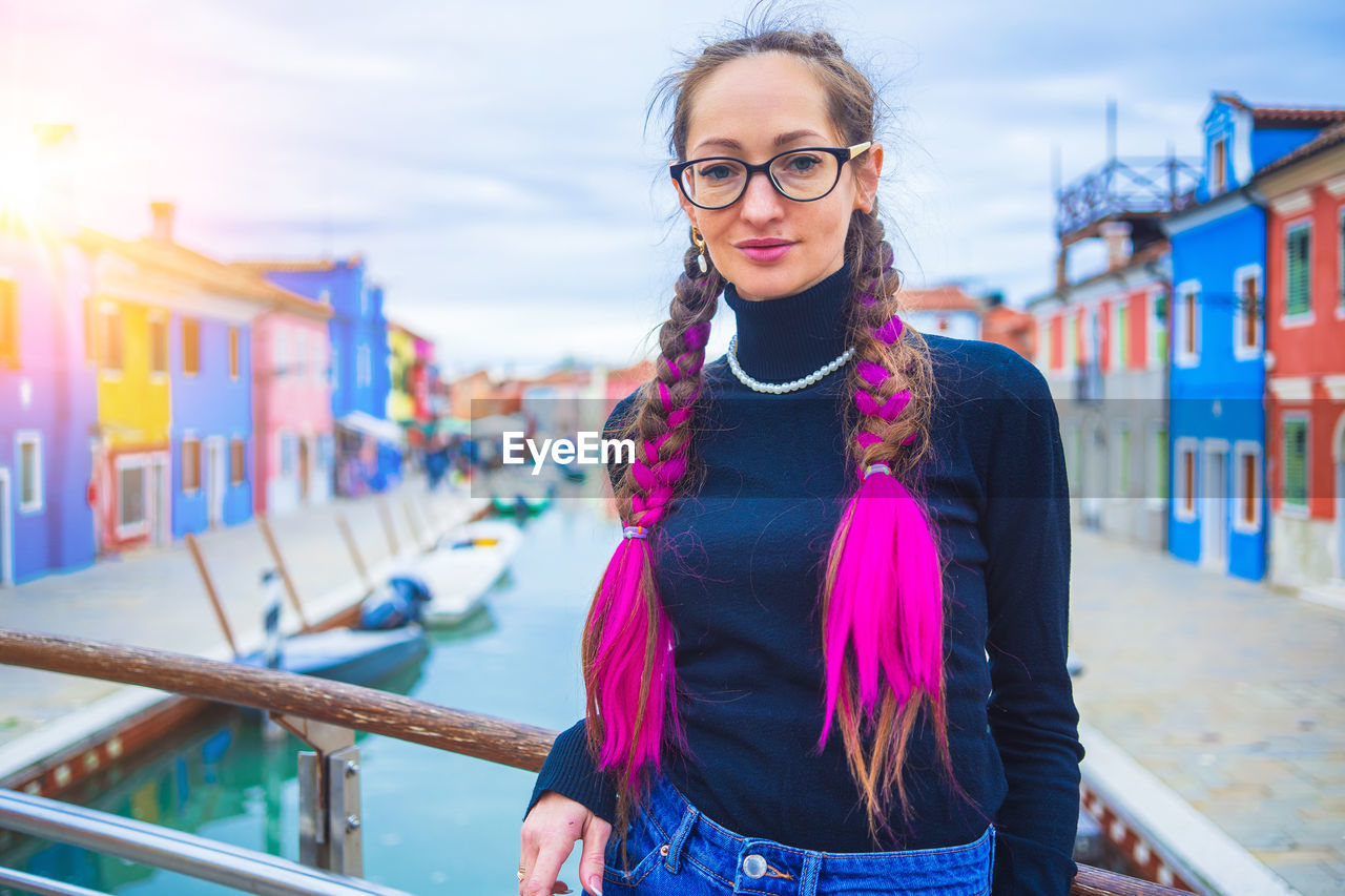 portrait of smiling young woman standing against railing