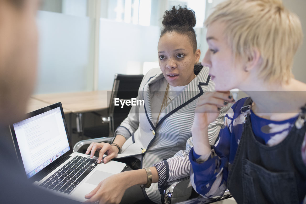 Group of young professionals collaborating in office with their laptops