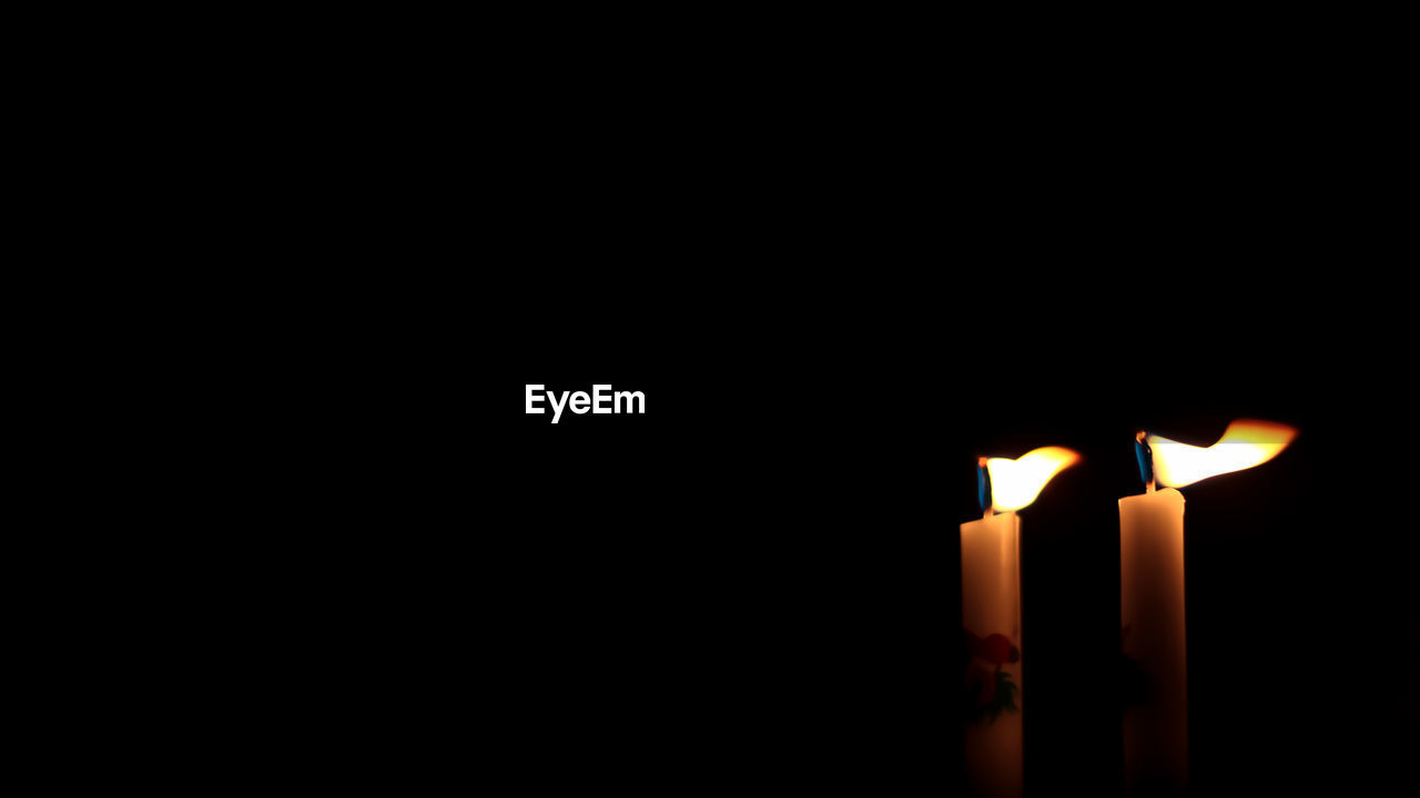 Close-up of illuminated candles against black background