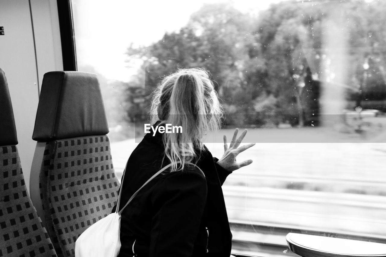 Rear view of woman looking through train window