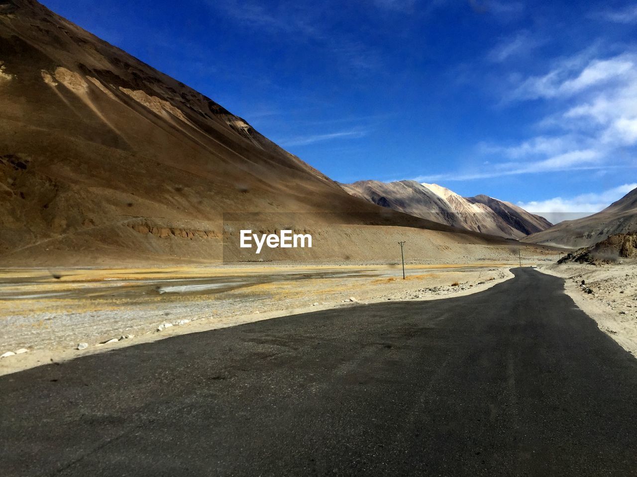 Road by mountains against sky