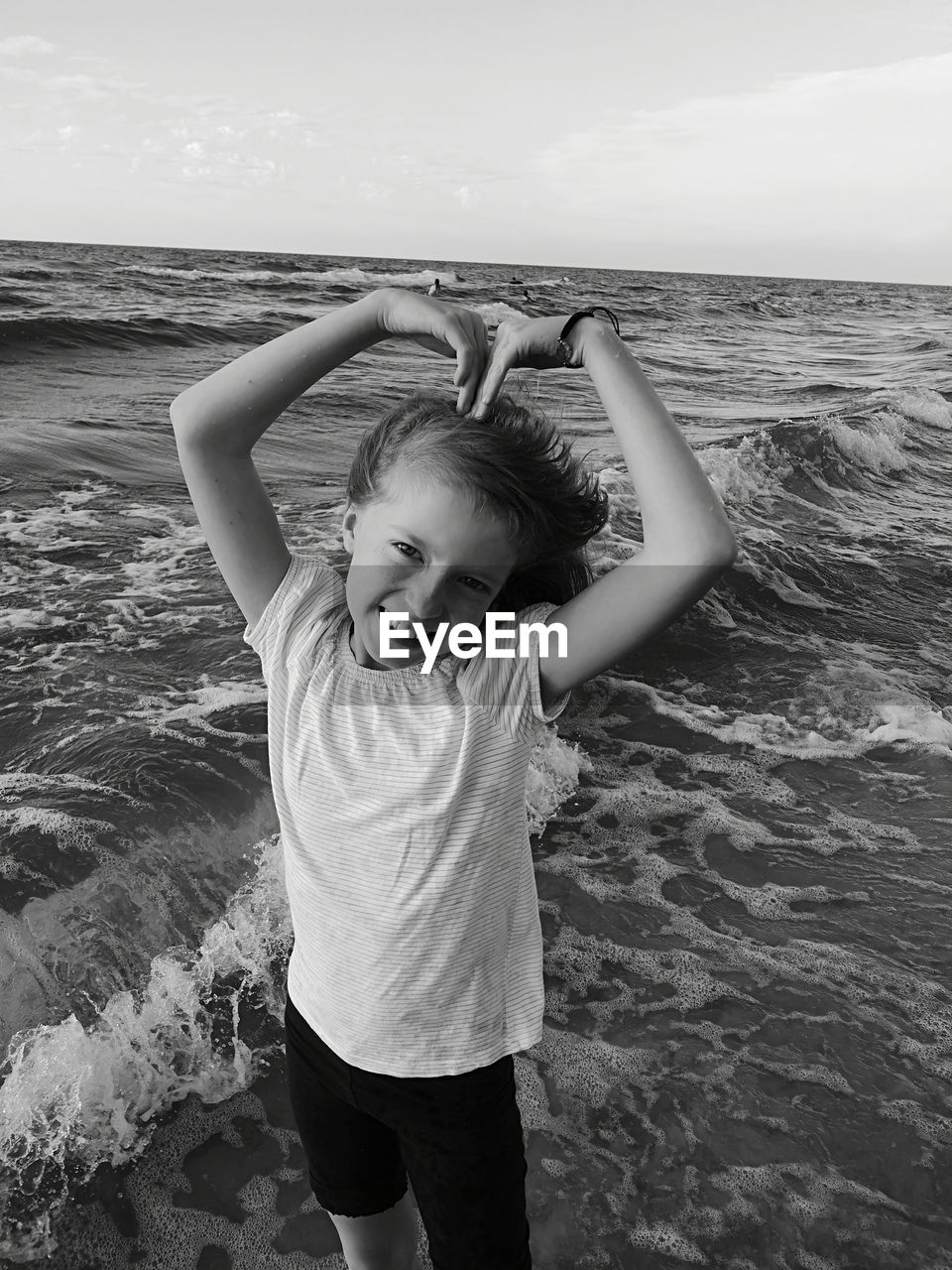 Portrait of girl gesturing while standing on shore at beach