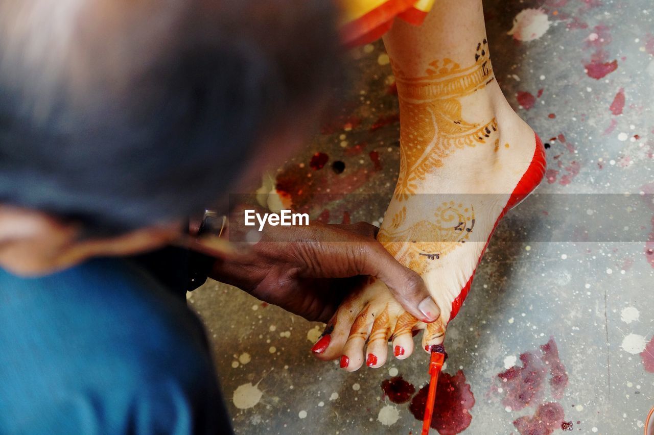 Close-up of woman applying red nail polish to bride