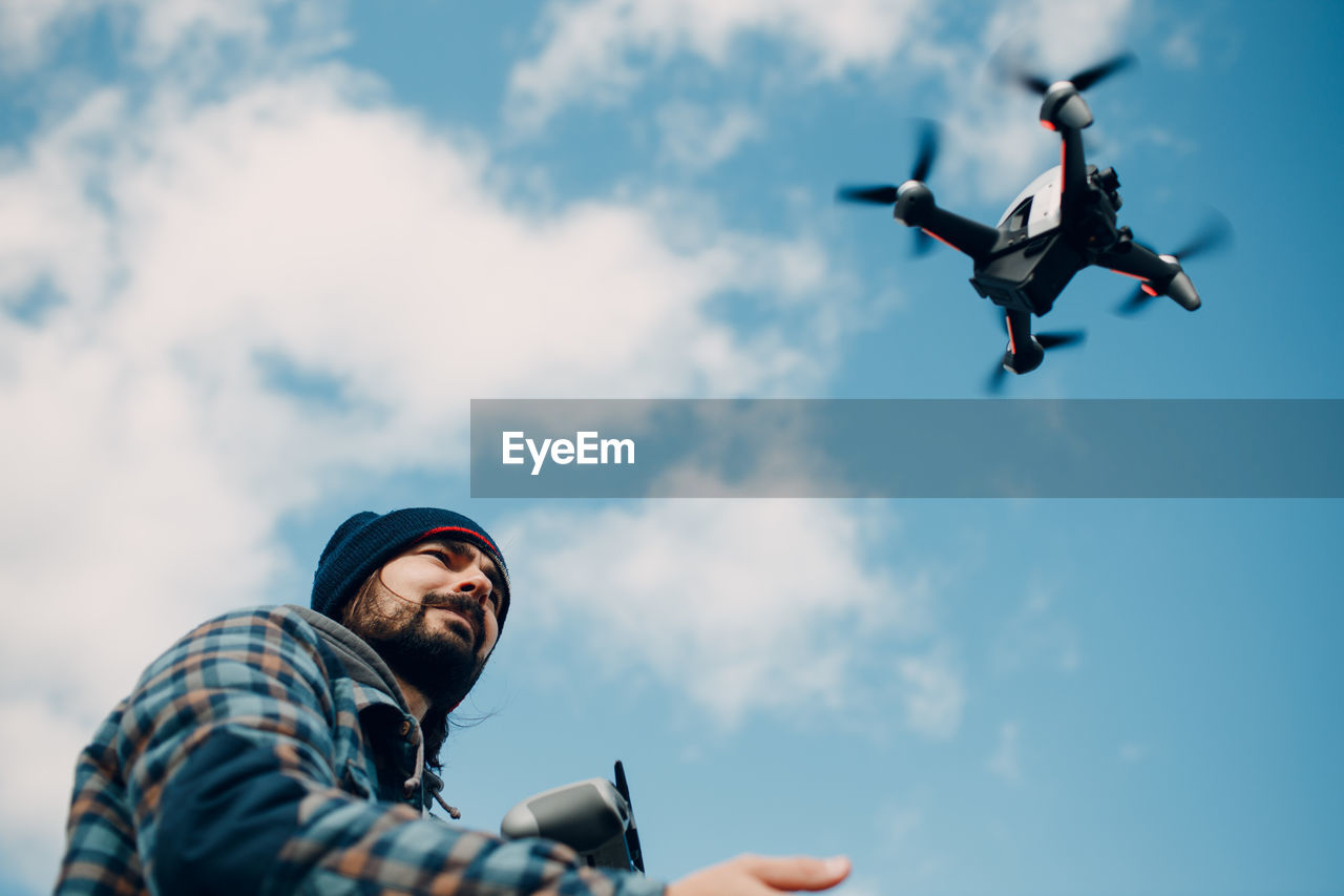 Low angle view of man flying against sky