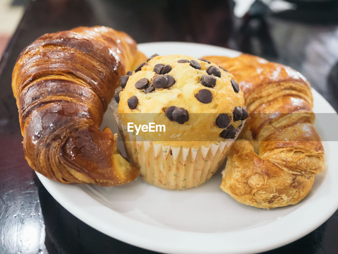 Close-up of muffin and croissants in plate on table