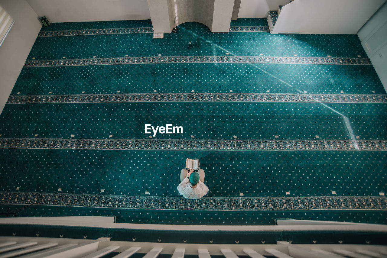 HIGH ANGLE VIEW OF YOUNG MAN SITTING ON CHAIR