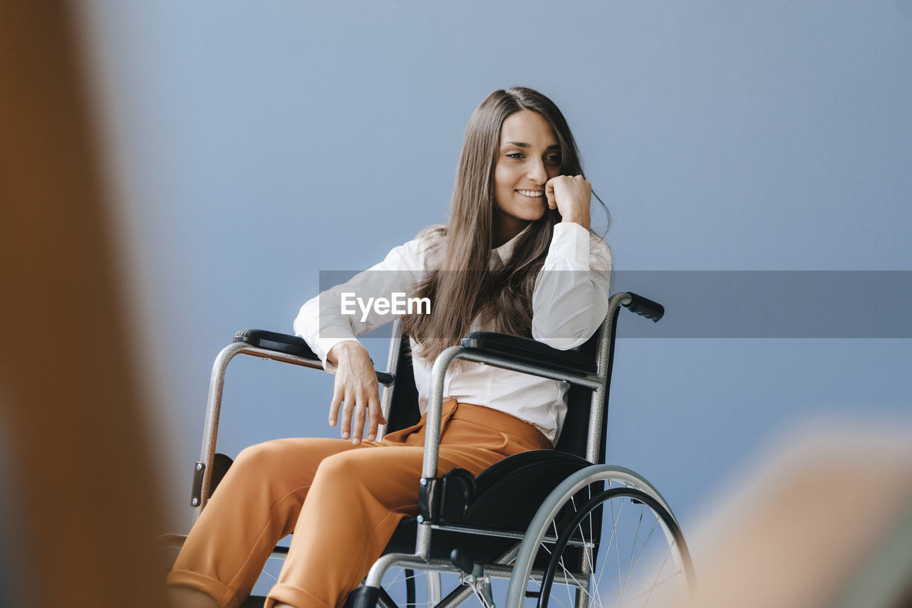 Young handicapped woman sitting in wheelchair, smiling