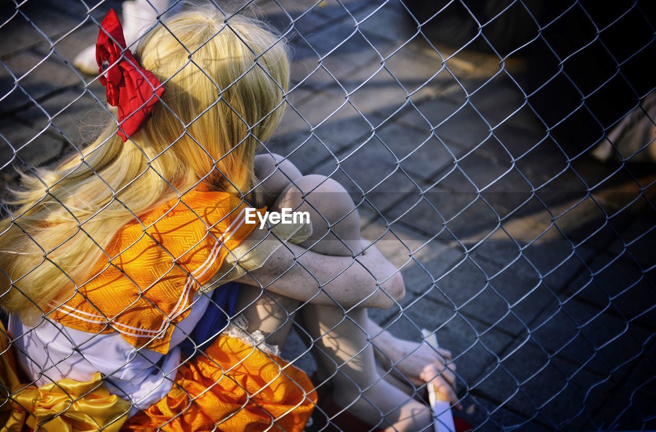 Girl sitting by chainlink fence